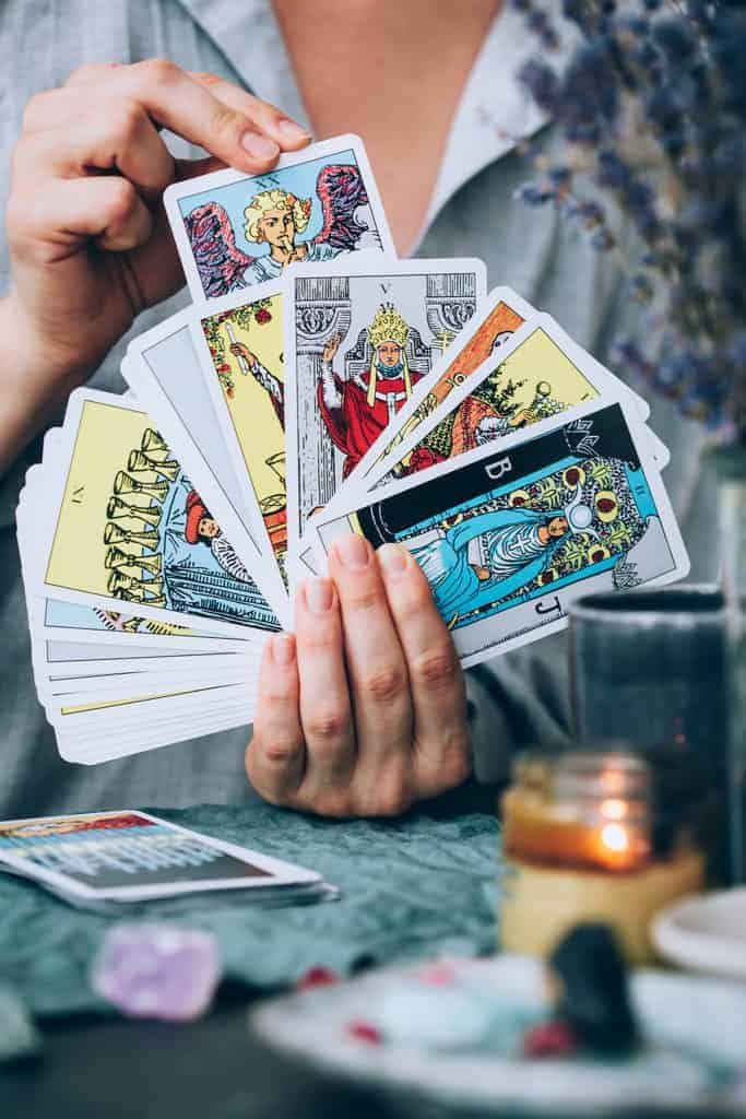 Mani che tengono un ventaglio di carte dei Tarocchi durante una sessione di counseling tarologico